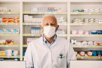 Wall Mural - Portrait of a senior pharmacy worker looking at the camera during corona virus.