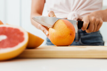 Wall Mural - Woman cutting grapefruits on cutting board for homemade fresh juice