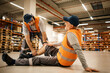 © Drazen - Young worker assists his colleague with leg injury while working at distribution warehouse.