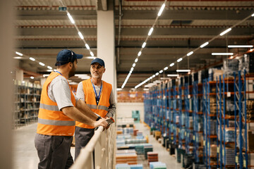 Poster - Male warehouse workers talk while working at storage compartment.