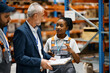© Drazen - African American warehouse worker and her colleague talking to company manager at storage compartment.