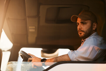 Young truck driver looking at side view mirror while driving in reverse.