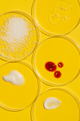 Wall Mural - Cosmetic swatches. Appearance of the texture of the cream, red mask, foam, gel and granules in petri dishes on a yellow background. Natural skincare products. Beauty concept for face and body care