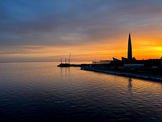 Wall Mural - Sunset at the city sea coast, orange and purple sunset, sky reflection