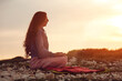 © astrosystem - Woman practicing yoga outdoors in sunset sunrise time.