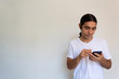 © Antonio Tanaka - portrait of a non binary hispanic man with long hair on a white background using a cell phone