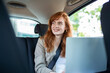 © Graphicroyalty - Pensive businesswoman with laptop in back seat of car. Young woman using a laptop in a car.