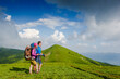 © olyphotostories - Young couple with backpacks hiking in the mountains and enjoying valley view