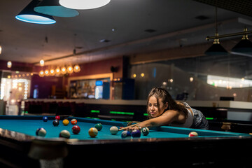 Wall Mural - cheerful young woman playing billiard in pub