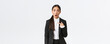 Shocked and offended young asian woman in suit pointing at herself with astounded panic face, being accused. Businesswoman looking insulted after being named, white background