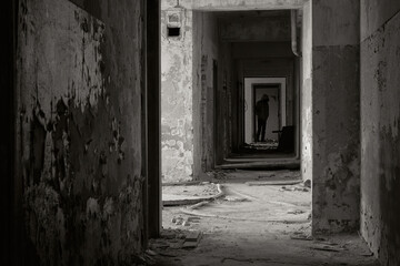 Ghost of a man in abandoned building. Silhouette in abandoned building. Ghost in corridor. Black and white photo.