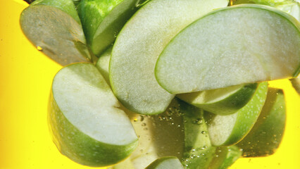 Wall Mural - Close up of green apple slices in water.