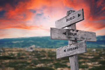build your dreams text quote caption on wooden signpost outdoors in nature. Stock sign words theme.