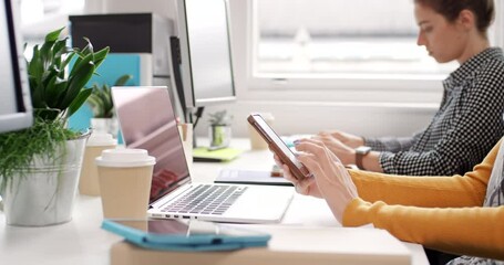 Aufkleber - Diverse group of businesspeople sitting at their desks typing on computer keyboards and. sending text messages on cellphones. Professional corporate team working on tech devices at their desk in a row