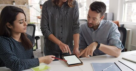 Aufkleber - A diverse group of young businesspeople collaborate during a meeting using a digital tablet, talking. Confident young businesswoman in a meeting with colleagues using wireless tablet device