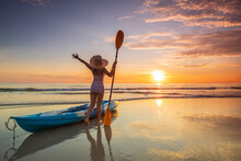 Young Lady Tourist And Canoe On The Beach With Sunset On The Sea At Phuket Province, Thailand.