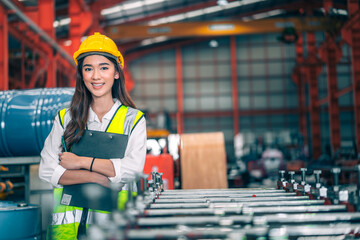 Portrait happy professional beautiful Asian woman industrial engineer/worker/technician with safety hardhat. Clipboard for inspect quality control machine in production steel manufacture factory plant