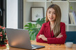 © Songsak C - Portrait of young businesswoman using laptop, smiling and looking at camera while sitting at office desk in modern office.