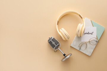 Wall Mural - Microphone, headphones, paper with word PODCAST and notebook on color background