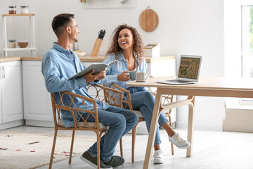Wall Mural - Happy young couple using modern laptop in kitchen