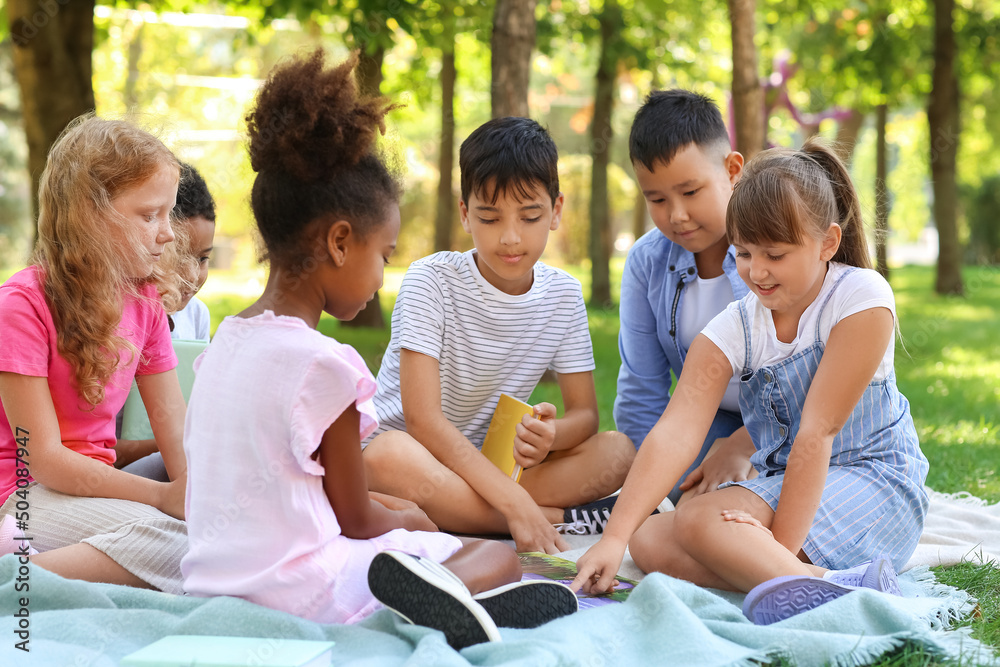 Little pupils reading book in park