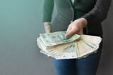 Fototapeta  - Kobieta wyciąga przed siebie ręce pełne pieniędzy, dużo pieniędzy w dłoni