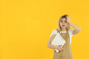 Wall Mural - Concept of occupation, young female waiter on yellow background