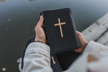 Bible in hands on the background of the river