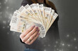 Polskie banknoty 200zł trzymane w dłoni, kobieta daje plik pieniędzy