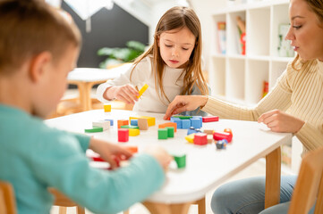 Wall Mural - Kindergarten children playing with colorful building blocks. Healthy learning environment. Learning through play.