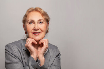 Wall Mural - Senior woman looking happy at camera on gray background