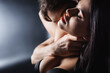 © LIGHTFIELD STUDIOS - Blurred man touching neck of passionate girlfriend on black background.