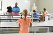 © WavebreakMediaMicro - Rear view of multiracial elementary students listening to african american young male teacher in lab