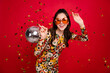 Portrait of attractive trendy girl holding disco ball dancing old school having fun isolated over bright red color background