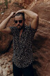 Zdjęcie lookbook, moda letnie męska, mężczyzna model w koszuli na tle skał.