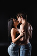 © LIGHTFIELD STUDIOS - Side view of passionate couple in jeans kissing on black background.