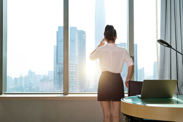 Wall Mural - Businesswoman using mobile phone in front of the window