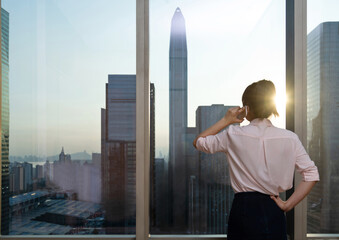 Wall Mural - Businesswoman using mobile phone in front of the window