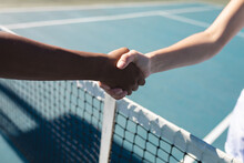 Cropped Hands Of Female Biracial Tennis Competitors With Handshake Over Net At Court On Sunny Day