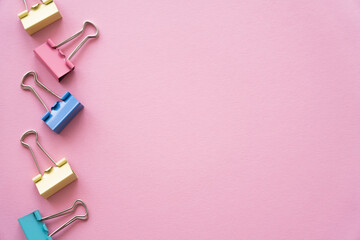 Wall Mural - flat lay of colorful pastel fold back clips on pink.