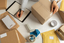 A Warehouse Worker Is Busy With The Logistics Of Shipping The Item In A Box For Postage.