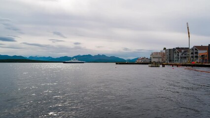 Wall Mural - Molde, Norway. View of the city center and fjord in Molde, Norway on a cloudy day. Time-lapse with moving ferry and modern buildings
