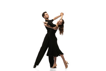 Two young graceful dancers wearing black stage outfits dancing ballroom dance isolated on white background. Concept of art, beauty, music, style.