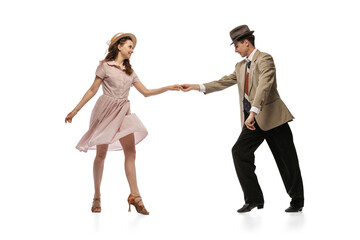 Young man and woman in vintage retro style outfits dancing social dance isolated on white background. Timeless traditions, 1960s american fashion style and art