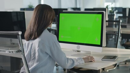 Asian Business Woman Working on Desktop Computer with Green Screen Mock Up Display in Busy Creative Office. Beautiful Diverse Female Manager Surfing Internet in Green Screen Notebook.