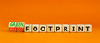 Green or carbon footprint symbol. Turned wooden cubes and changed words Carbon footprint to Green footprint. Orange background. Business ecological green or carbon footprint concept. Copy space.