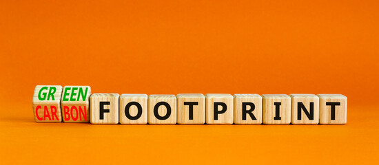 Wall Mural - Green or carbon footprint symbol. Turned wooden cubes and changed words Carbon footprint to Green footprint. Orange background. Business ecological green or carbon footprint concept. Copy space.