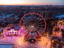 Aerial Close View On Illuminated Ferris Wheel. Winter Kharkiv City Center Recreation Area In Evening Lights. Amusement Gorky Central Park In Sunset