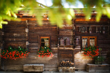 Wooden House With Red Lowers And Cowbells