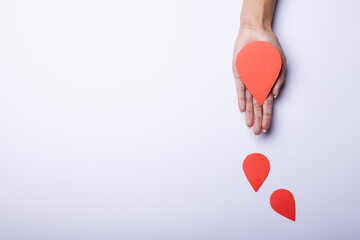 Wall Mural - Cropped hand of african american mid adult woman with paper bloods on white background, copy space